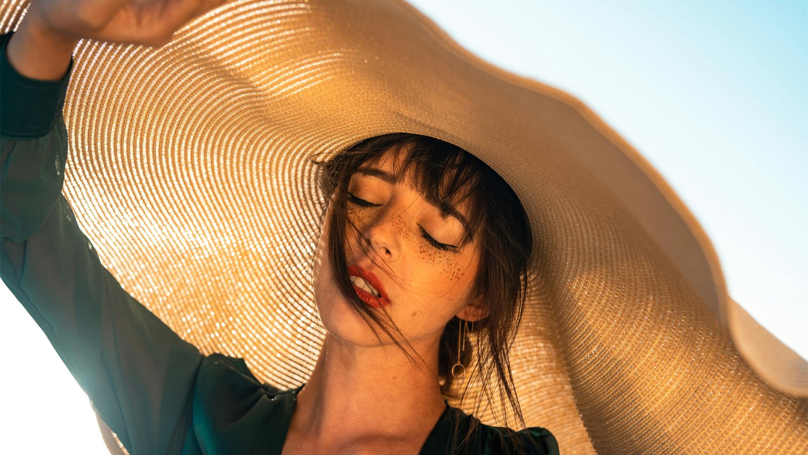 woman shading her head from the summer sun to illustrate sun cause hair loss